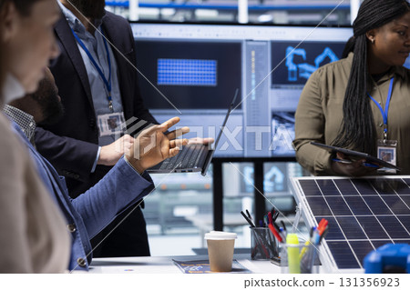 Photovoltaics factory engineer meeting with investors using laptop to highlight key elements of solar panel design. Manager using notebook to do presentation of industrial energy solutions, close up Photovoltaics factory engineer meeting with investors using laptop to highlight key elements of solar panel design. Manager using notebook to do presentation of industrial energy solutions, close up 131356923