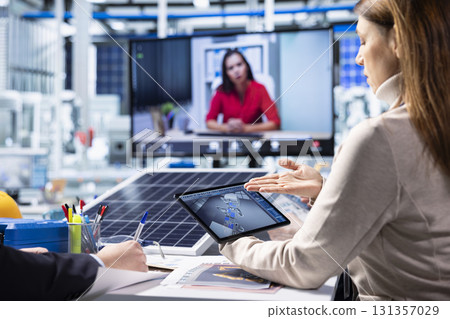 Photovoltaics factory shareholders discuss upgrades, visualizing floor designs with 3D software in video call. Solar panels plant investors look at CAD simulations during teleconference, brainstorming 131357029