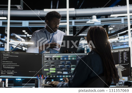 Computer scientist in data center using PC to visualize artificial intelligence neural networks made up of interconnected nodes. Server farm employee oversees AI systems processing information 131357069