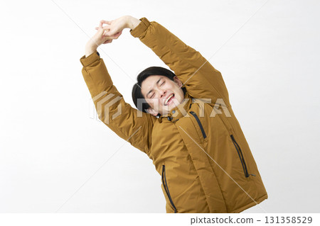 Man wearing down jacket stretching white background 131358529
