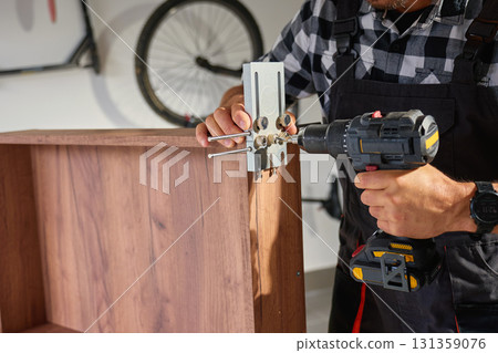 Carpenter drilling wooden panel using jig tool for precise holes Carpenter drilling wooden panel using jig tool for precise holes 131359076