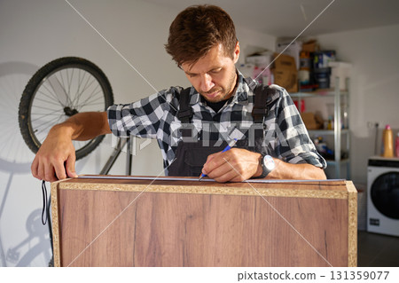 Carpenter measuring wooden boards in workshop Carpenter measuring wooden boards in workshop 131359077