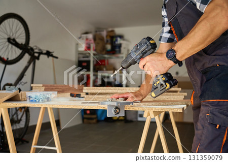 Carpenter drilling wooden panel using jig tool for precise holes 131359079