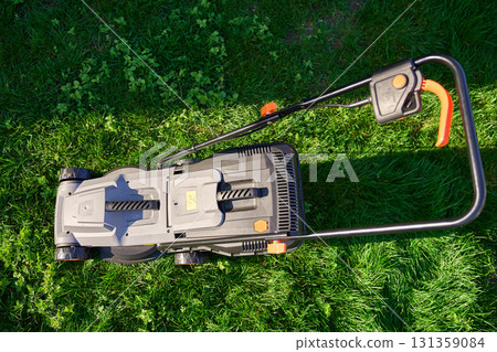 Electric lawnmower on green grass in backyard 131359084
