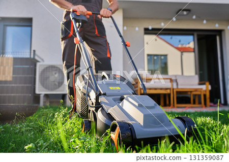 Man mowing lawn with electric mower in backyard 131359087