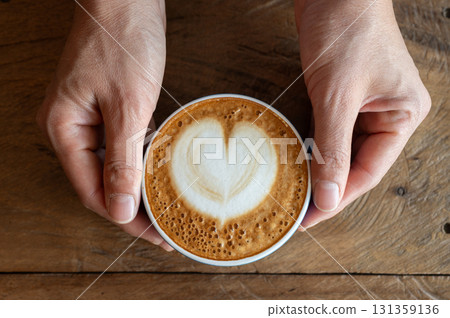 Woman hands holding a cup of hot Cappuccino coffee before drinking. The taste of cappuccinos can be described as creamy, smooth, and balanced. Woman hands holding a cup of hot Cappuccino coffee before drinking. The taste of cappuccinos can be described as creamy, smooth, and balanced. 131359136