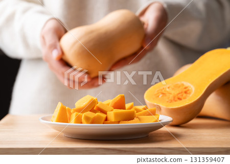 Butternut squash pumpkin holding by woman hand and preparing for cook Butternut squash pumpkin holding by woman hand and preparing for cook 131359407