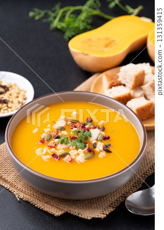 Butternut squash pumpkin soup with granola in a bowl on black background Butternut squash pumpkin soup with granola in a bowl on black background 131359415