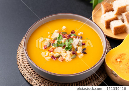 Butternut squash pumpkin soup with granola in a bowl on black background 131359416
