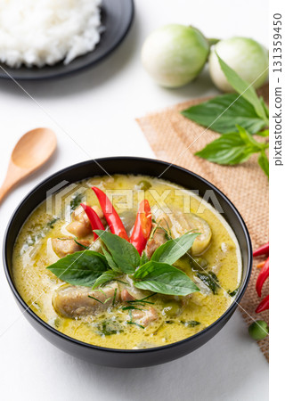 Thai green curry chicken in black bowl with rice and ingredients on white background 131359450