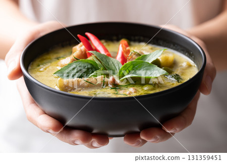 Thai green curry chicken in black bowl holding by hand 131359451