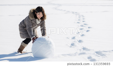 一位女士在白雪皚皚的冬日場景中享受堆雪人 131359693