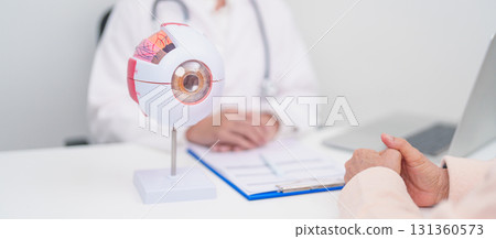 Elderly Patient consulting Doctor to Eye disease, Senior Medical Diagnosis. Anatomy Eye model for Cataract, Glaucoma, Age Related Macular Degeneration, Diabetic Retinopathy, Vitreous, health concept 131360573