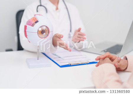 Elderly Patient consulting Doctor to Eye disease, Senior Medical Diagnosis. Anatomy Eye model for Cataract, Glaucoma, Age Related Macular Degeneration, Diabetic Retinopathy, Vitreous, health concept 131360580