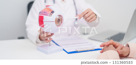 Elderly Patient consulting Doctor to Eye disease, Senior Medical Diagnosis. Anatomy Eye model for Cataract, Glaucoma, Age Related Macular Degeneration, Diabetic Retinopathy, Vitreous, health concept 131360583