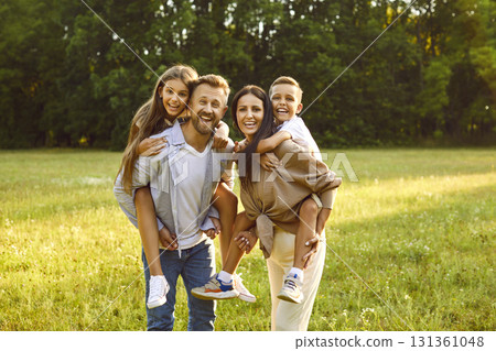 Portrait of happy family with son and daughter standing in the summer park and looking at camera. 131361048