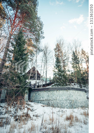 A serene countryside scene featuring a cozy cabin surrounded by snow-covered trees and mountains. The landscape evokes a sense of tranquility and mindfulness. 131361050