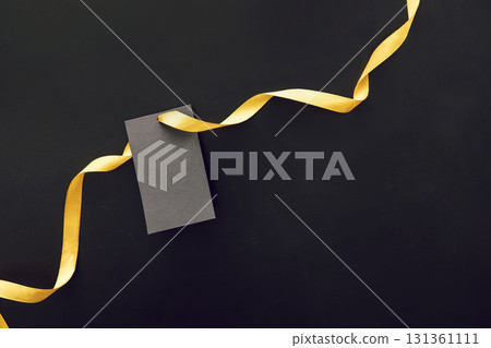 A black gift tag with a yellow ribbon on a dark background. Ideal for Black Friday sale promotions and marketing materials. 131361111