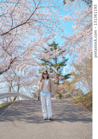 Woman tourist sightseeing Sakura Cherry Blossom in Spring. Happy traveler travel at Saigyo Modoshi no Matsu over Matsushima Bay in Matsushima, Miyagi Prefecture, Japan. Famous Landmark and Vacation 131361193