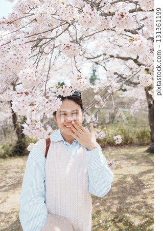 Woman tourist wearing wedding ring under Sakura Cherry Blossom tree. Happy traveler travel in Saigyo Modoshi no Matsu park over Matsushima Bay in Matsushima, Miyagi, Japan. Vacation and travel 131361199