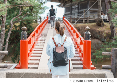 Woman tourist walking cross Sukashibashi bridge to the Zuiganji Godaido or National Treasure, a temple building on a small island in Matsushima Bay in Matsushima, Miyagi Prefecture, Tohoku, Japan 131361200