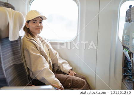 young asian woman sitting on the express train near the window. Tourist Enjoying and traveling by train young asian woman sitting on the express train near the window. Tourist Enjoying and traveling by train 131361280