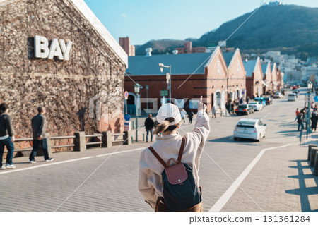 Woman tourist Visiting in Hakodate, happy Traveler sightseeing Kanemori Red Brick Warehouse in spring season. landmark and popular for attractions in Hokkaido, Japan. Travel and Vacation concept 131361284