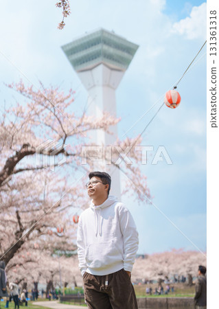 man tourist sightseeing Goryokaku Tower park with Sakura Cherry Blossom in Spring, happy traveler travel in Hakodate city, Hokkaido, Japan. famous Landmark, Japan Travel and Vacation destination 131361318