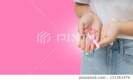 Person holds a pink ribbon that symbolizes cancer awareness 131361479