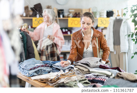 adult woman stands at the counter with pants and chooses them 131361787