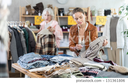 adult woman stands at the counter with pants and chooses them adult woman stands at the counter with pants and chooses them 131361806