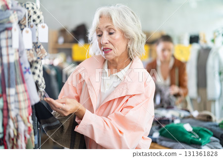 Mature woman customer examine and choose scarf in store Mature woman customer examine and choose scarf in store 131361828