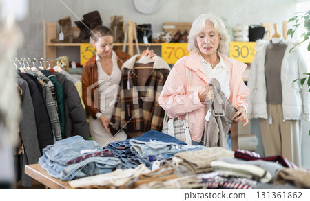 older woman holds woolen pants in her hands in a store older woman holds woolen pants in her hands in a store 131361862