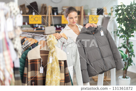 Young woman chooses sweater in clothing store Young woman chooses sweater in clothing store 131361872