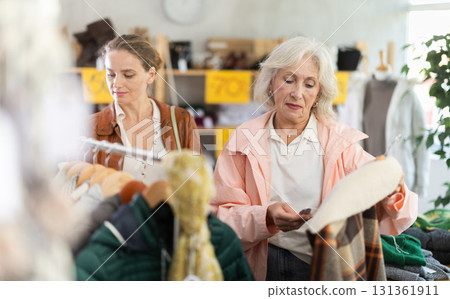 Mature woman customer examine and choose plaid jacket in store Mature woman customer examine and choose plaid jacket in store 131361911