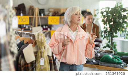 Elderly woman chooses outerwear in store Elderly woman chooses outerwear in store 131361920