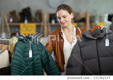 Woman choosing a down jacket in a clothing store Woman choosing a down jacket in a clothing store 131362137