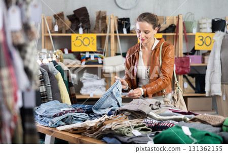 European woman customer examine and choose jeans trousers in store 131362155