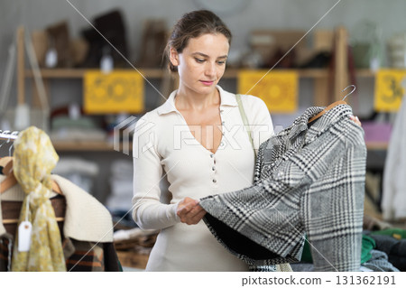 Woman customer examine and choose jacket in store Woman customer examine and choose jacket in store 131362191