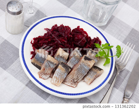 Sliced marinated herring with boiled grated beetroot and greens 131362202