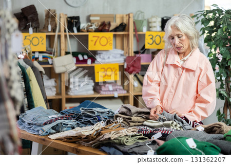 Elderly woman choosing down sweater in clothing store Elderly woman choosing down sweater in clothing store 131362207