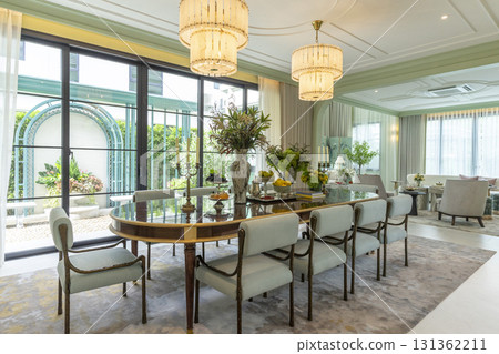 Beautiful luxurious traditional style modern dining room with bouquets of flowers on the table. Elegance dinning table with luxurious pendant. 131362211
