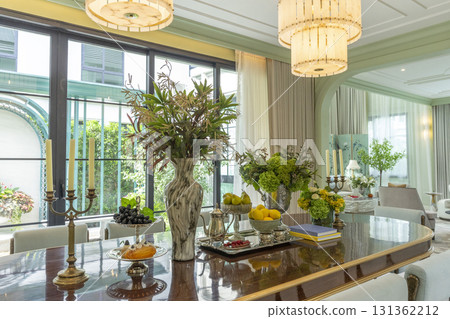 Beautiful luxurious traditional style modern dining room with bouquets of flowers on the table. Elegance dinning table with luxurious pendant. 131362212