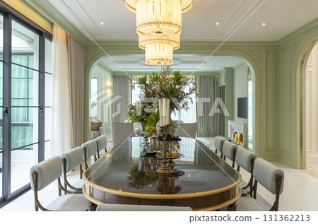 Beautiful luxurious traditional style modern dining room with bouquets of flowers on the table. Elegance dinning table with luxurious pendant. Beautiful luxurious traditional style modern dining room with bouquets of flowers on the table. Elegance dinning table with luxurious pendant. 131362213