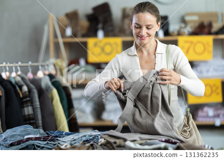 European woman customer examine and choose trousers in store 131362235