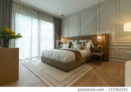 Luxury large modern bedroom in white and brown colors. On the sides are two bedside tables with lamps. Luxury large modern bedroom in white and brown colors. On the sides are two bedside tables with lamps. 131362261