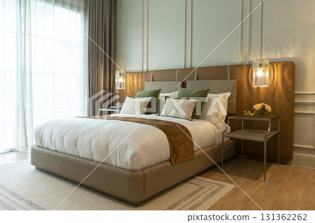 Luxury large modern bedroom in white and brown colors. On the sides are two bedside tables with lamps.  131362262