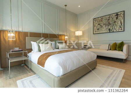 Luxury large modern bedroom in white and brown colors. On the sides are two bedside tables with lamps. Luxury large modern bedroom in white and brown colors. On the sides are two bedside tables with lamps. 131362264