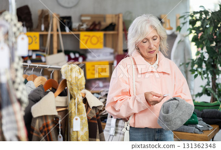 Senior woman customer examine and choose hat. Senior woman customer examine and choose hat. 131362348