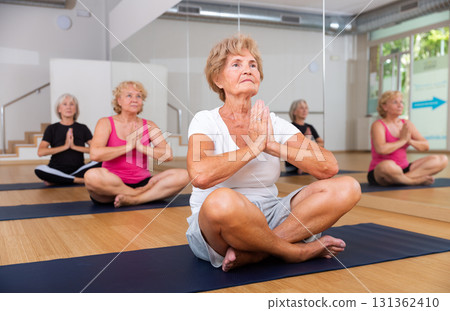 Senior women sitting in lotus pose during group training 131362410